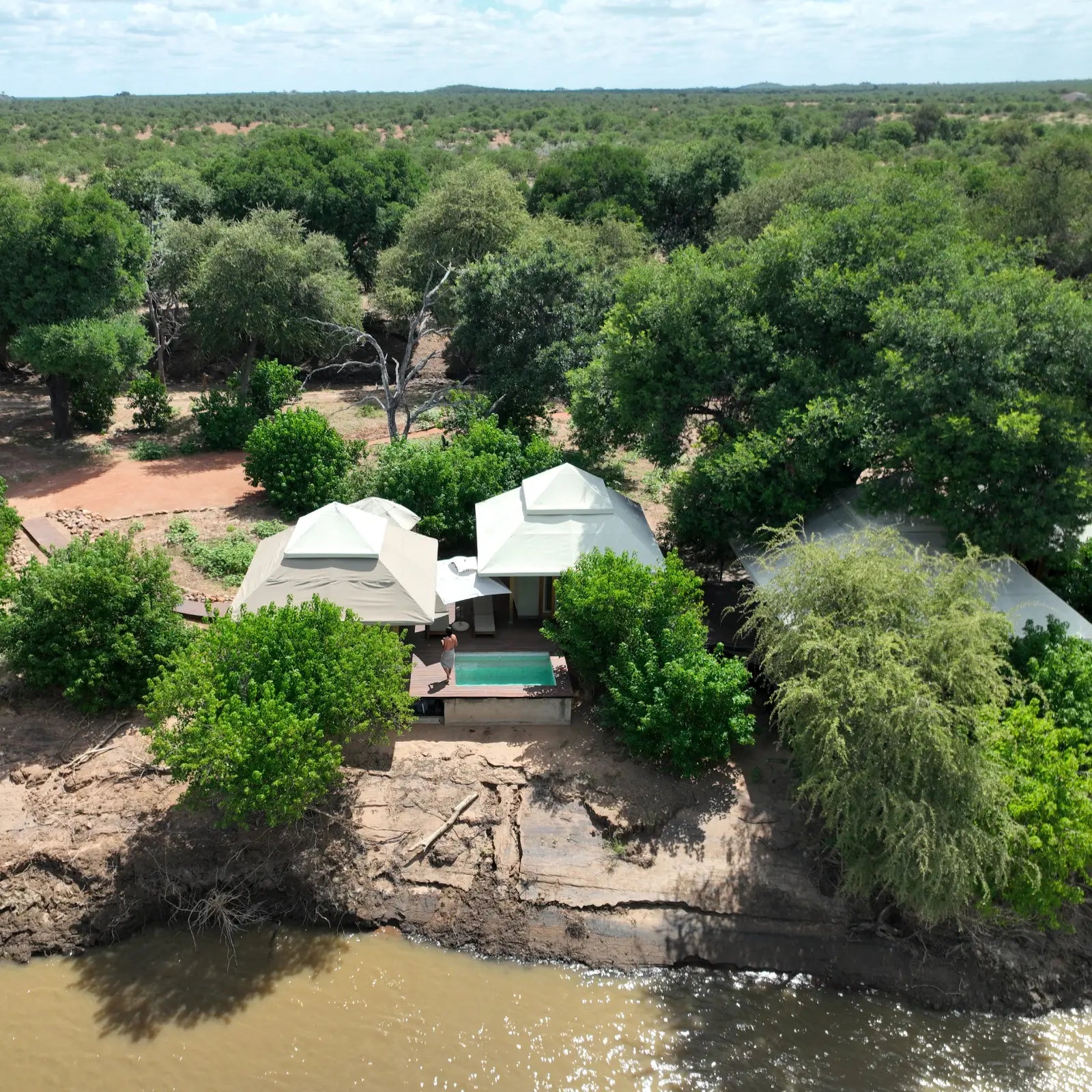 Aerial view of a house surrounded by trees and water